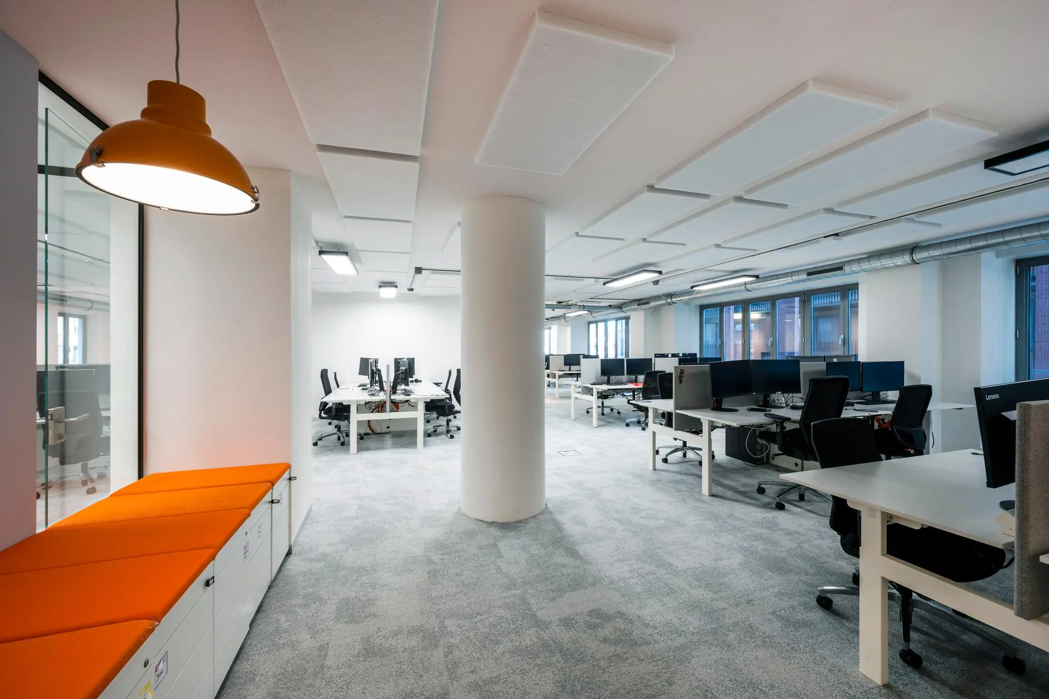 Modern en strak ingericht kantoorpand aan de Harry Banninkstraat met open werkplekken en oranje zitbank.